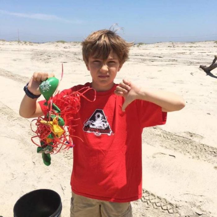 Niño sosteniendo basura en sus manos luego de limpiar una playa 