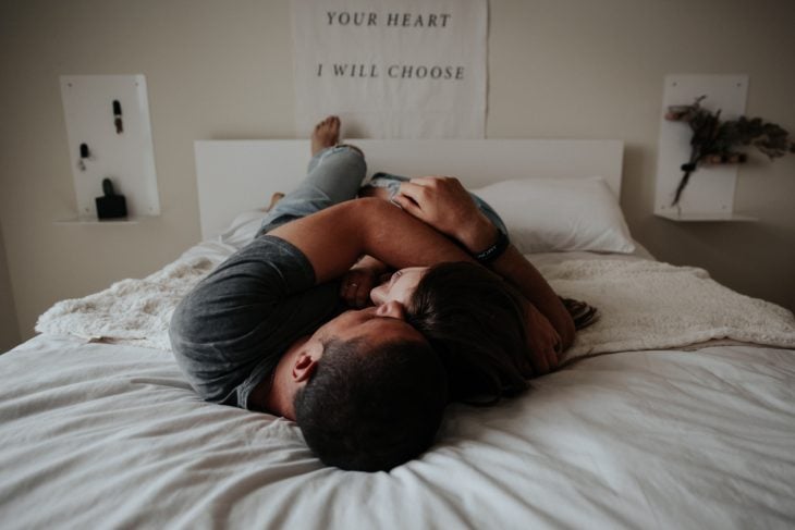 Una pareja acostada en una cama abrazándose