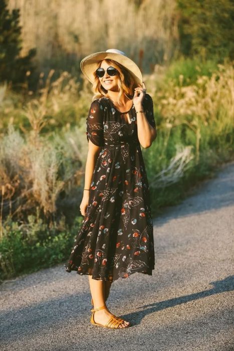 Chica en el campo usando vestido con flores y sombrero