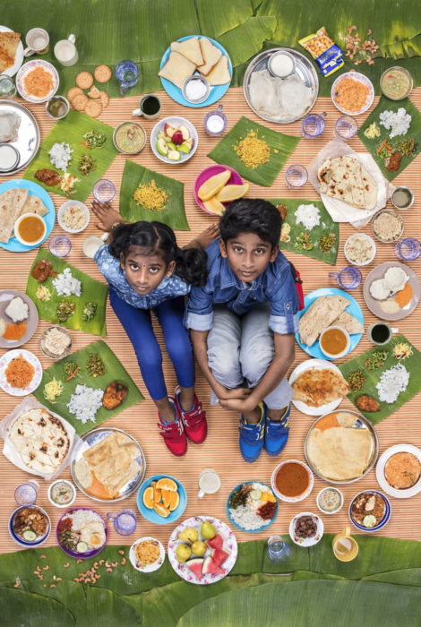 Par de hermanos sentados sobre una alfombra melón, rodeados de comida, royecto fotográfico de Gregg Segal