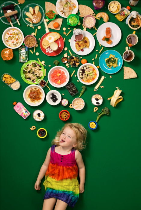 Niña recostada en una alfo,bra verde, rodeada de comida, proyecto fotográfico de Gregg Segal