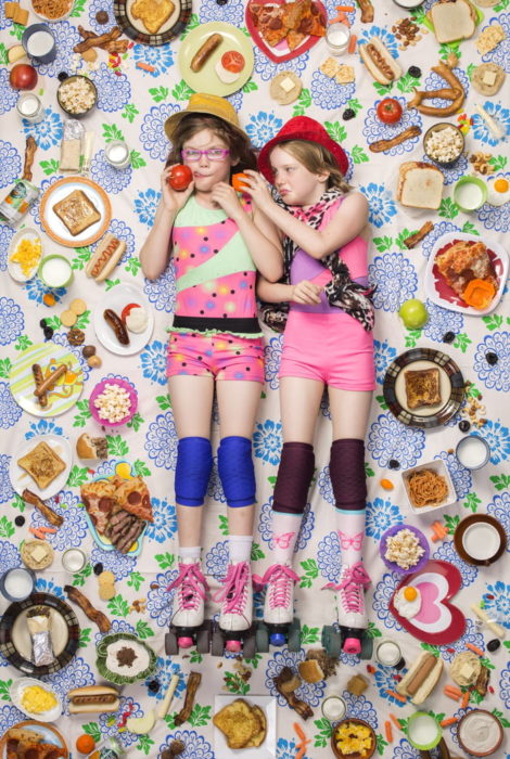 Hermanas recostadas en el piso, rodeadas de comida frutal, proyecto fotográfico de Gregg Segal