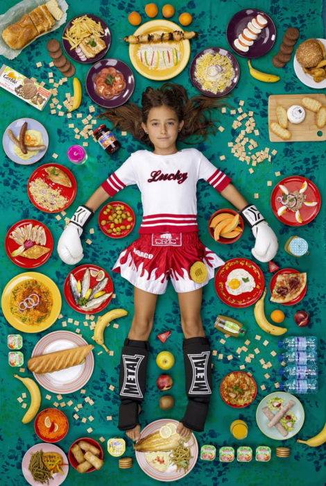 Niña usando ropa deportiva, recostada en la alfombra verde, proyecto fotográfico de Gregg Segal