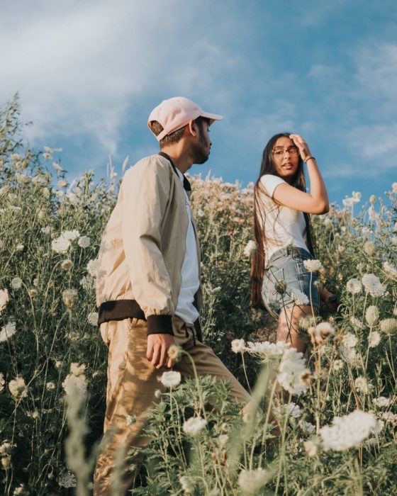 Chico siguiendo a una chica a través de un campo con margaritas