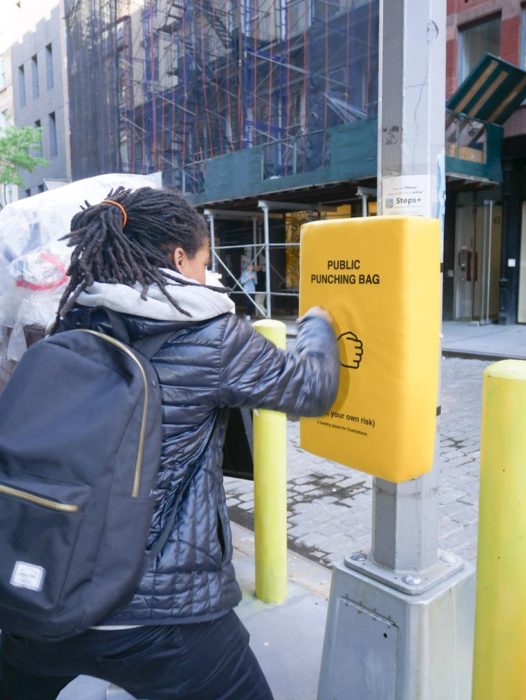 Chica golpeando un saco de box colocado en un poste para que la gente se desestrese 