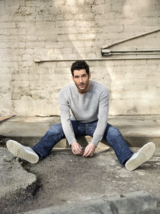 Actor de serie de Netflix, Lucifer, Tom Ellis; hombre de suéter gris sentado en la banqueta 