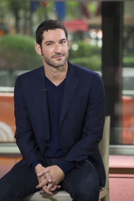 Actor de serie de Netflix, Lucifer, Tom Ellis; hombre de traje azul sentado en una silla