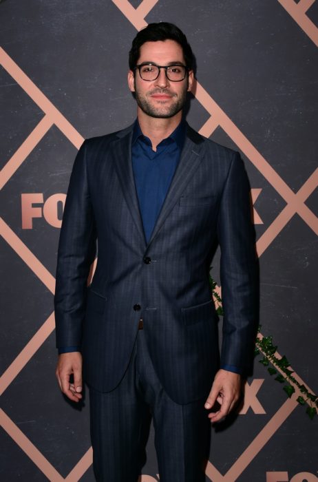 Actor de serie de Netflix, Lucifer, Tom Ellis; hombre con barba, lentes de armazón grueso y traje azul marino