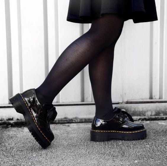 Piernas de mujer con medias negras y zapatos de plataforma ancha