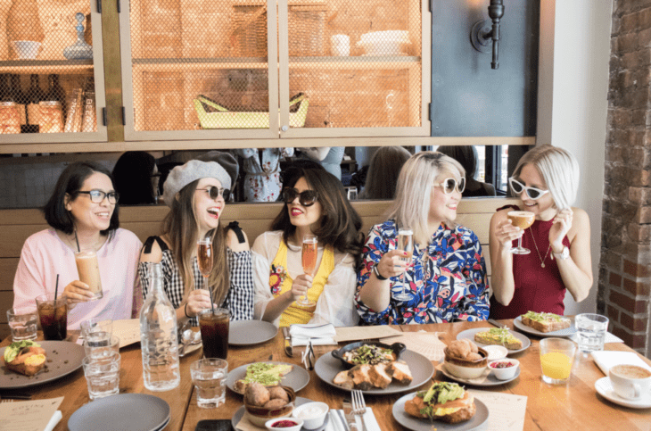 Chicas sentadas en un restaurante desayunando junto a sus amigas 