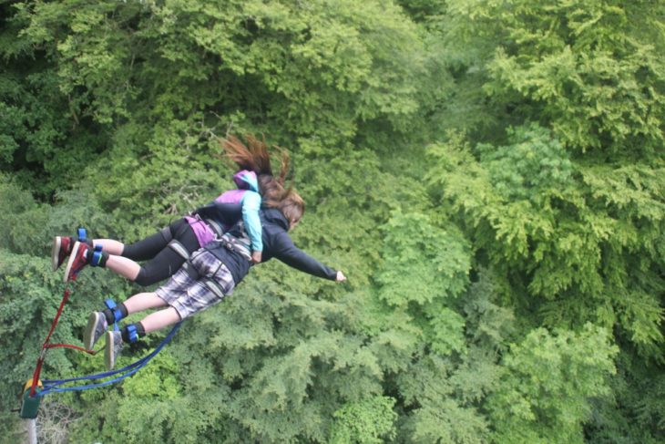 Chicas saltando de un bungee en medio del bosque