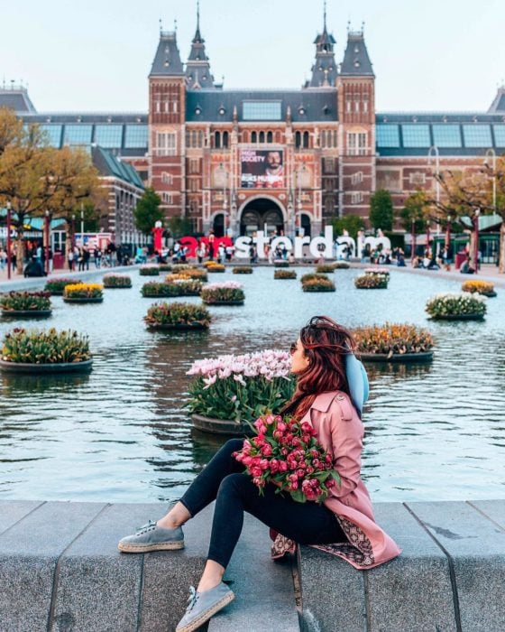 Chica con ramo de flores frente a río Amstel en Ámsterdam