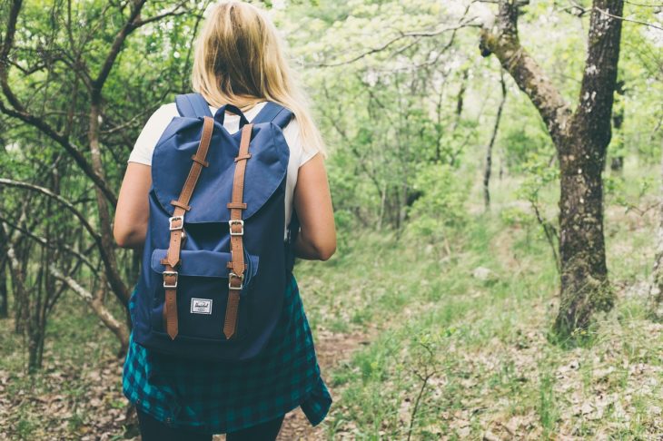 una mujer con una mochila azul camina por un un bosque