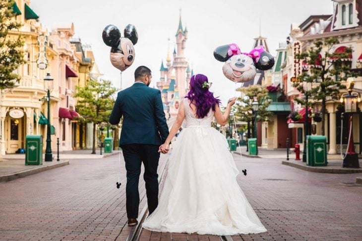 Precios de boda en Disneylandia; pareja de recién casados en el Magic Kingdom con globos de Mickey y Minnie Mouse