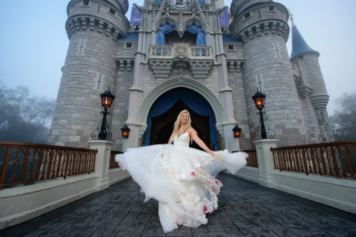Precios de boda en Disneylandia; novia con vestido blanco y flores frente a castillo de parque de diversiones