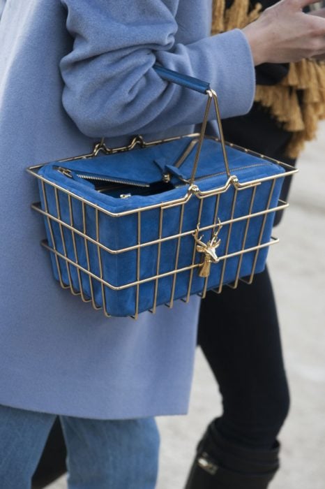 Chica sujetando unabolsa en forma de canasta de supermercado de color azul 