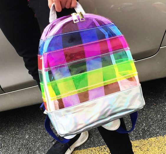 mujer sosteniendo mochila transparente de colores