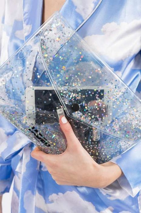 Mujer sosteniendo cartera transparente con glitters