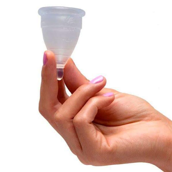 una mano sostiene una copa menstrual transparente