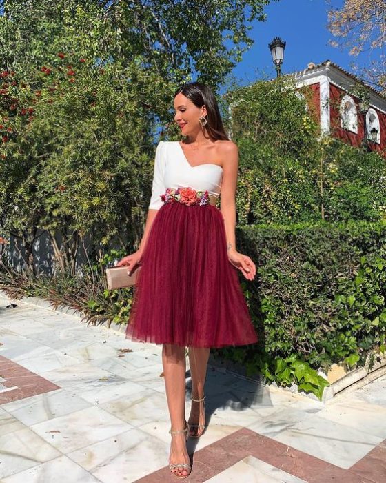 Chica en un jardín modelan su outfit con falda de tul en color vino