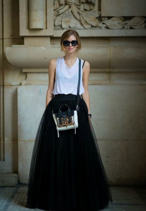 Chica con falda de tul larga, bolso cruzado y gafas oscuras modelando 