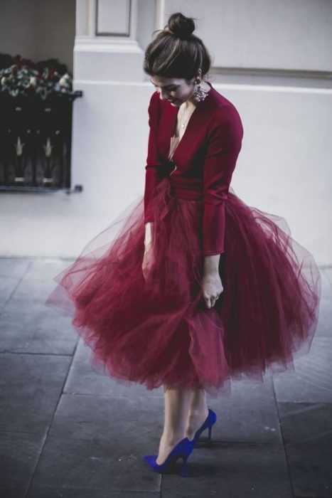 Chica con outfit color vino mirando hacia abajo para observar el piso