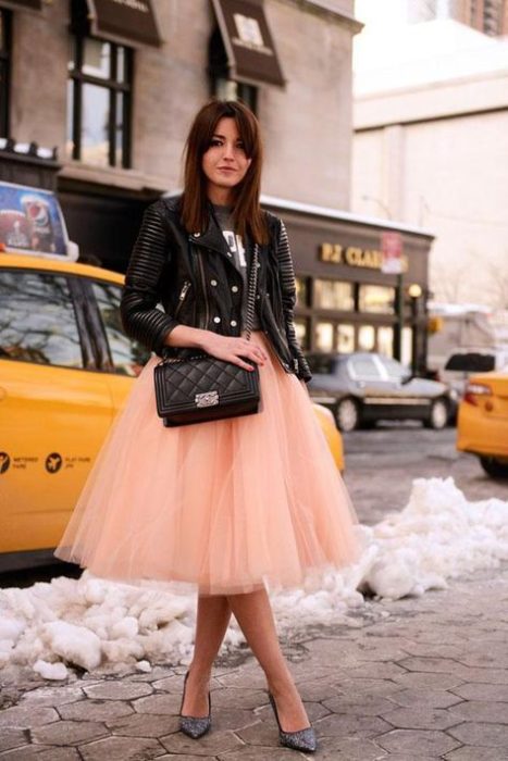 Chica modelando su falda de tul en tono color melón con chaqueta de cuero en negro