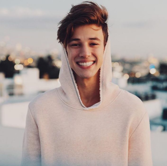 Actor Cameron Dallas sonriendo mientras posa para una fotografía durante sus vacaciones 