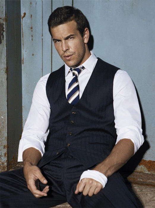 Mario Casas sentado sobre una banca mientras posa para una sesión de fotos de la revista GQ