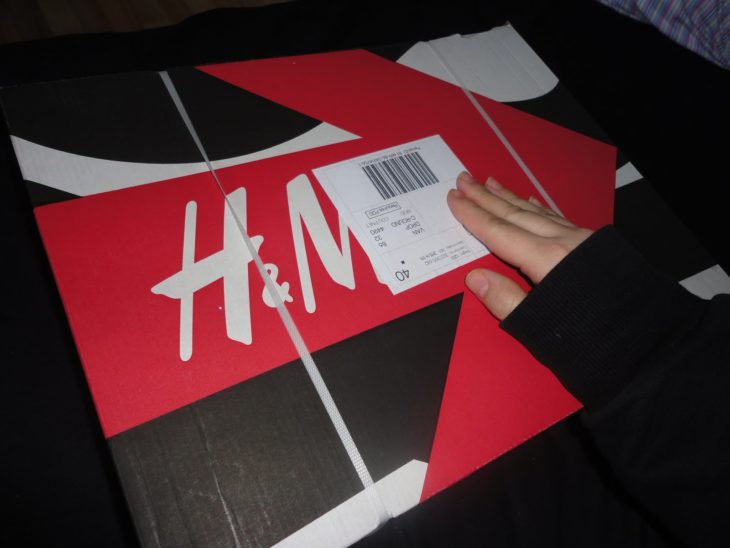 una mano revisa la etiqueta de un envío a domicilio de H&M