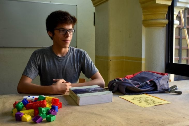 Axel Roberto Ruíz Ortega dentro de una biblioteca revisando sus apuntes