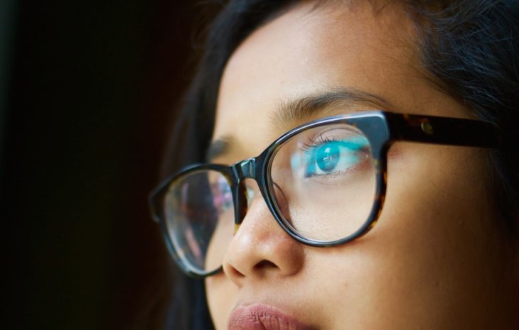 cara de una joven con lentes sobre fondo negro