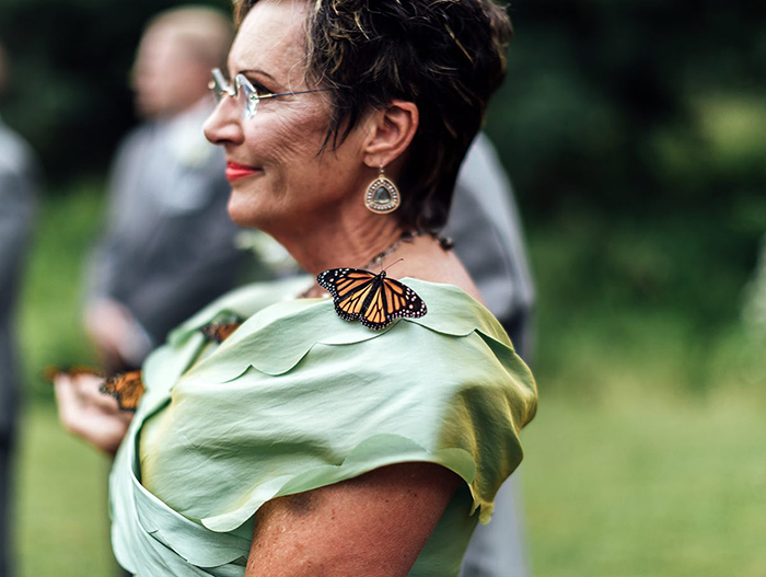 Mariposa monarca sobre el hombro de una mujer en un jardín