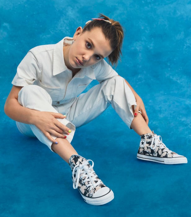 Millie Bobby Brown sentada mirando hacia el frente mostrando sus tenis