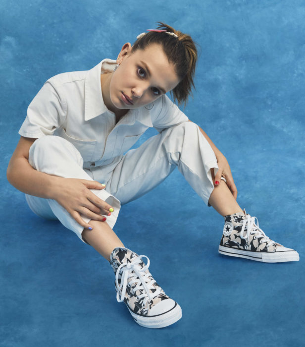 Millie Bobby Brown sentada mirando hacia el frente mostrando sus tenis