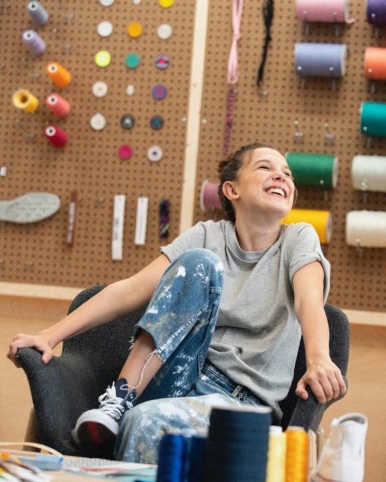 Millie Bobby Brown sentada en una silla, sonriendo