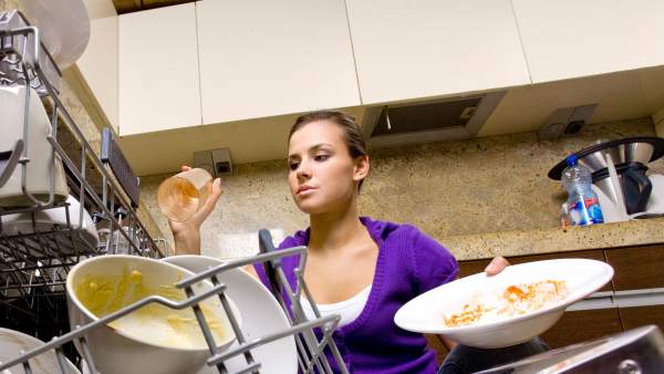 una mujer joven acomoda trastes en una cocina, toma contra picada