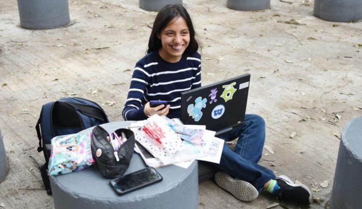 Nataly sonriendo con su computadora y papeles escolares