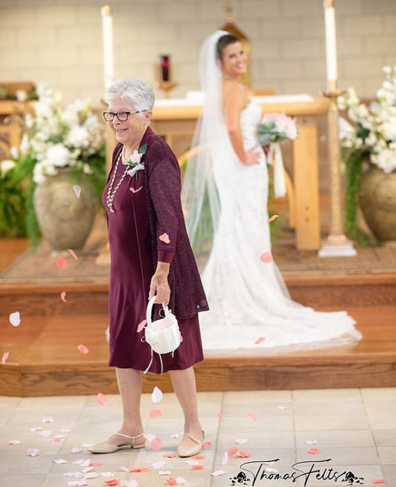 Abuela lanzando pétalos mientras su nieta camina hacia el altar 
