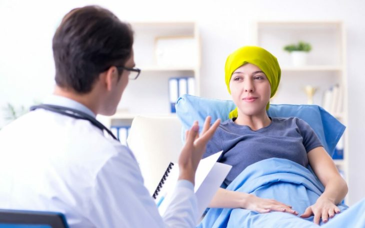 una joven con la cabeza cubierta con un turbante amarillo en una cama de hospital observa a un doctor