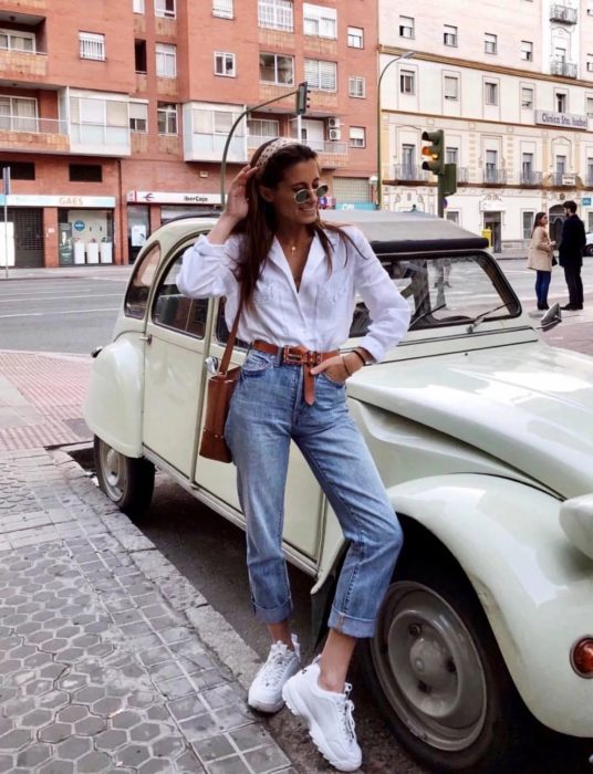 Chica usando un pantalón de mezclilla hasta los tobillos, blusa de color blanco y uglye sneakers 