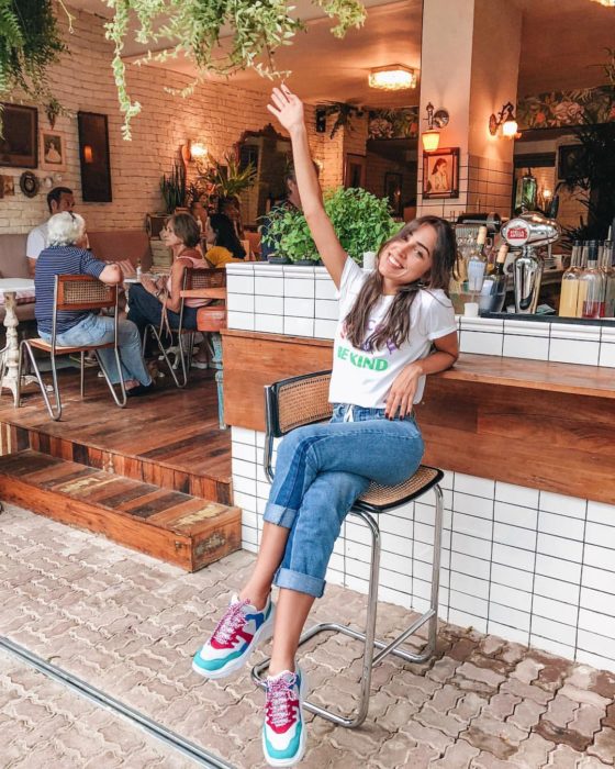 Chica usando jeans, blusa blanca y tenis ugly de colores 