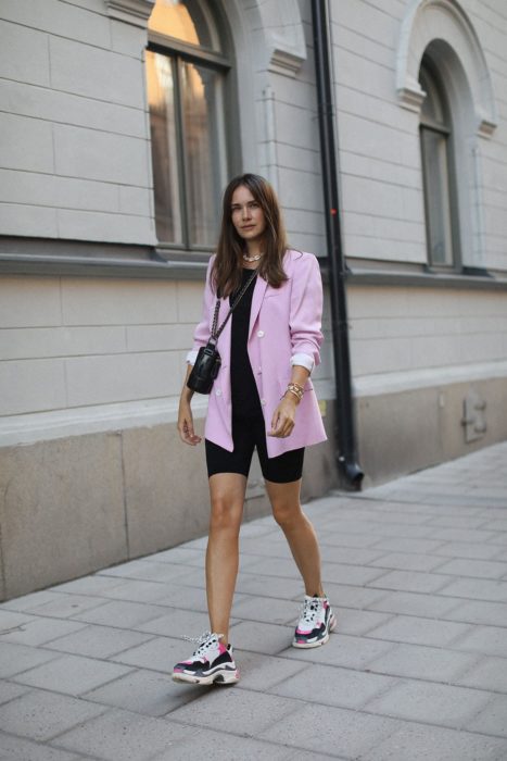 Chica usando unas mayas para ciclista con un blazer rosa y uglye shoes 