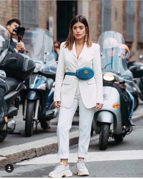 Chica usando un traje sastre con unos ugly sneakers y una riñonera 