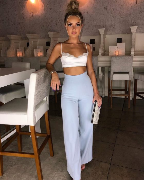 Chica usando un pantalón de color azul estilo palazzo con un crop top de color blanco 