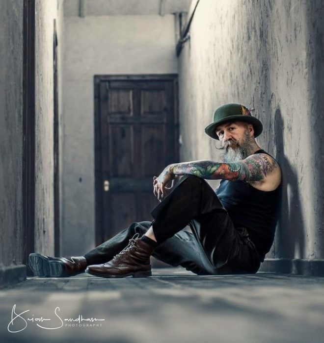 Pip sentado en el pasillo de un edifico modelando su outfit vintage