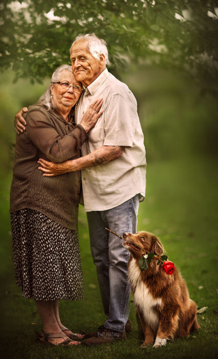 Abuelos junto a su perros parados en un jardín, abrazados, fotografía de Sujata Setia