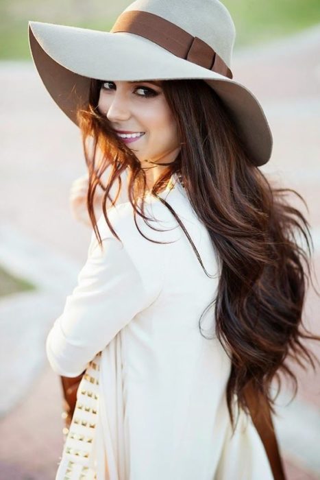 Chica de cabello largo, sonriendo, usando sombrero estilo campesino 