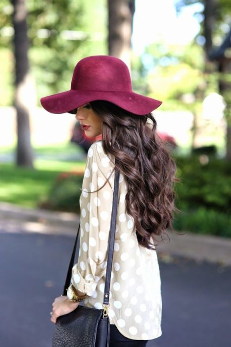 Chica modelando de perfil su sombrero color vino 