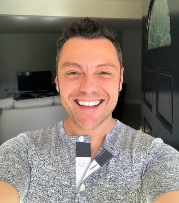 Tiziano ferro sonriendo feliz mientras se toma una selfie en su casa 